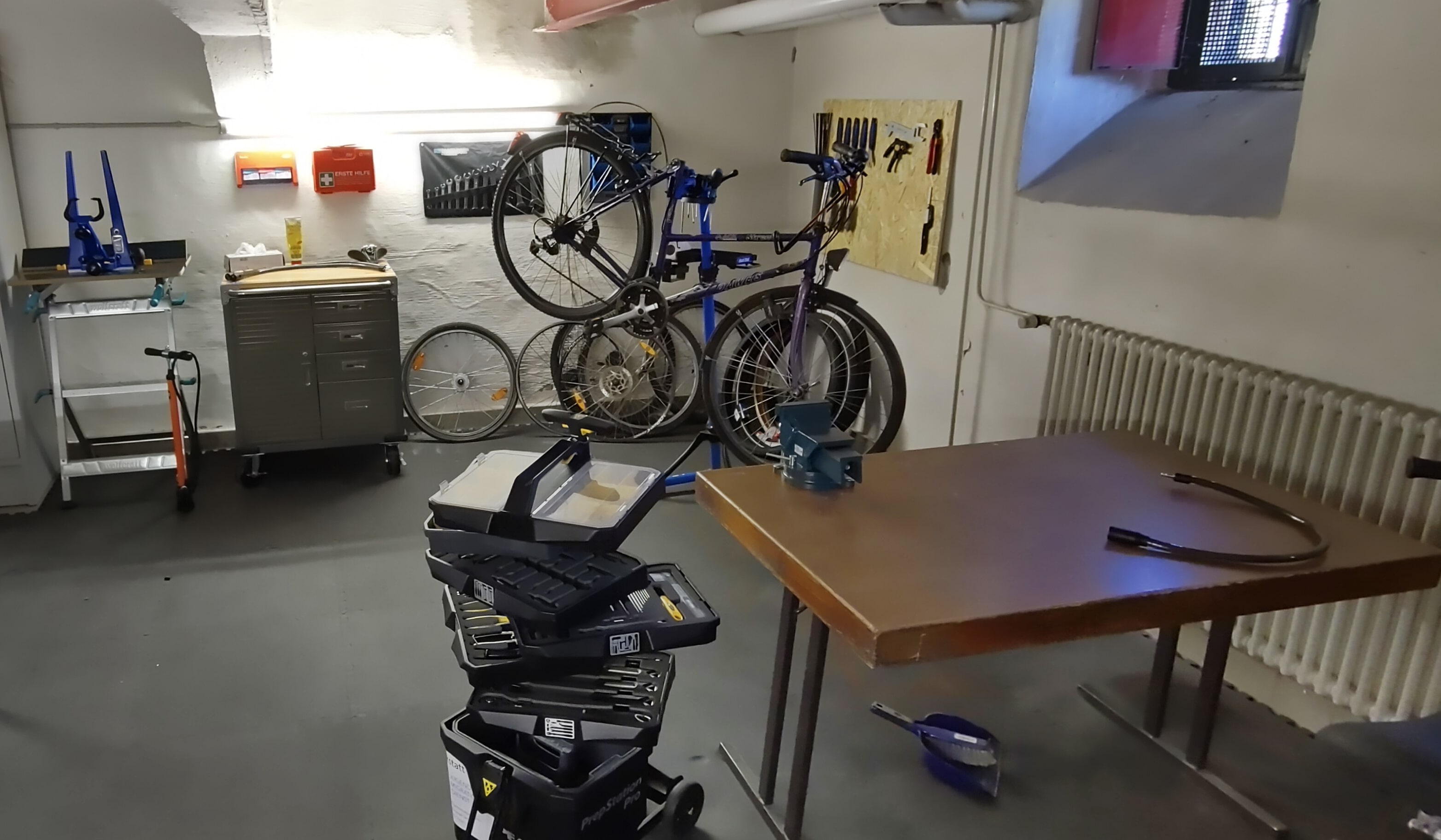 In einem Keller befindet sich ein Tisch, Werkzeuge und Fahrräder.