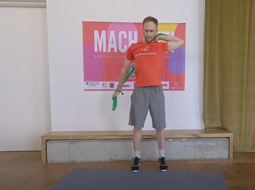 Der Anleiter zeigt in einem Video die Sportübungen. Mit einem Theraband wird die Flexibilität trainiert.