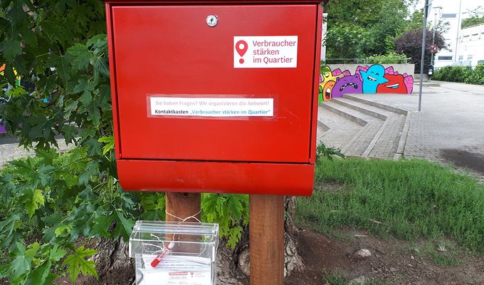 Ein roter Briefkasten vor einem Baum.